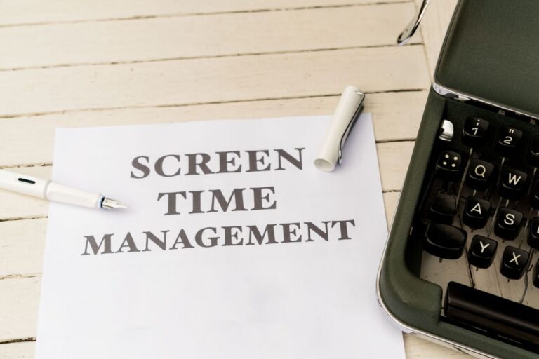 Typewriter with paper titled 'Screen Time Management' on a wooden table.