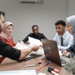 A diverse group of professionals engaging in a collaborative office meeting, sharing ideas and working on a project.