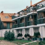 Contemporary multi-storey apartments in Nida, Lithuania showcasing wooden balconies and green surroundings.