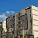 Contemporary apartment building with balconies, captured on a sunny day with a clear blue sky.