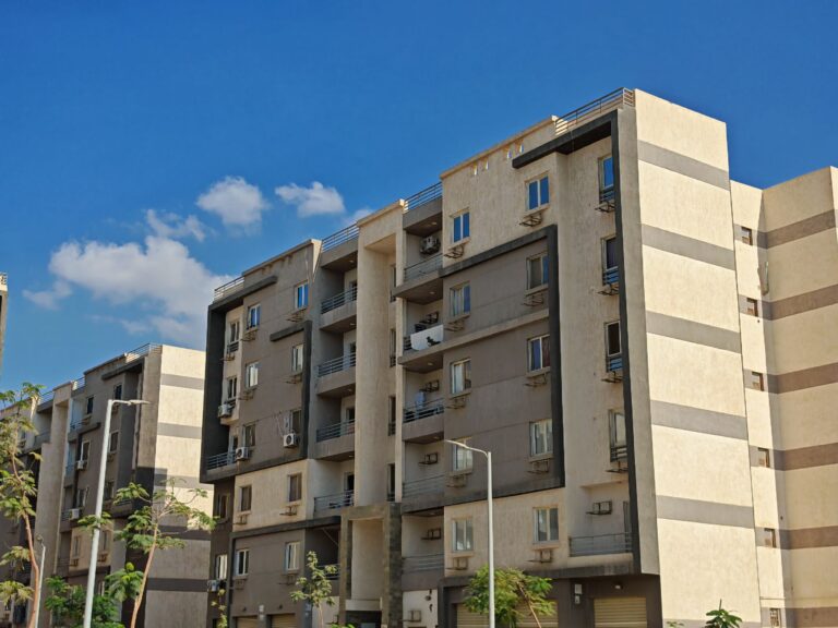 Contemporary apartment building with balconies, captured on a sunny day with a clear blue sky.